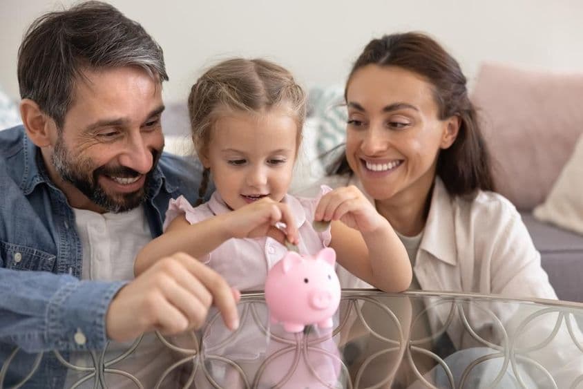 Pais felizes ensinando filha a economizar dinheiro.