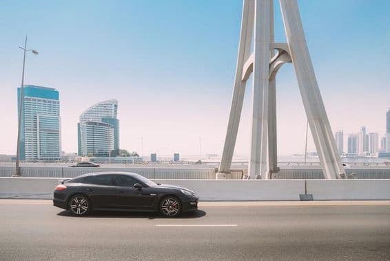 Carro Porsche Panamera preto se movendo em uma rua da cidade de Dubai.