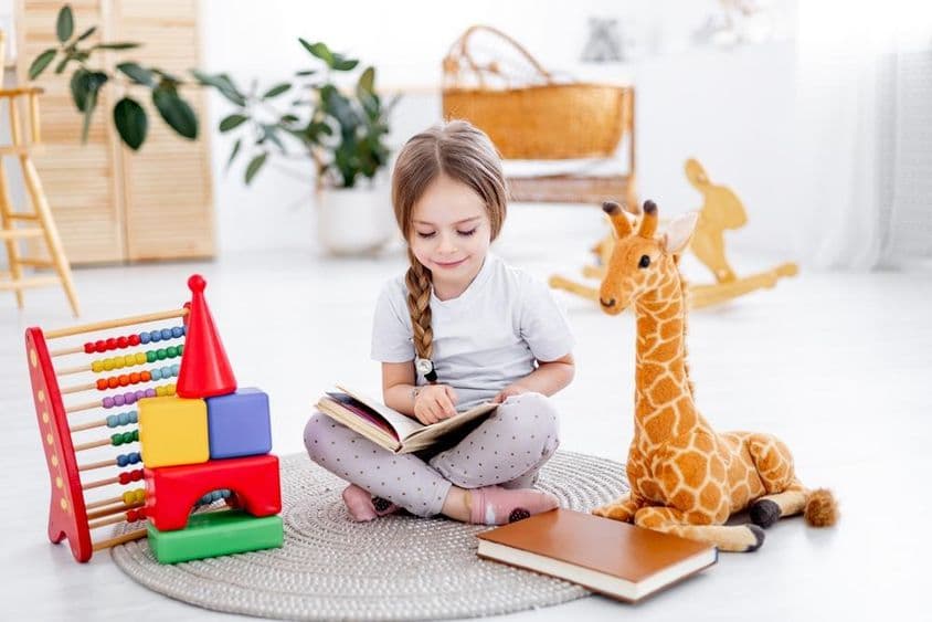 Uma menina entre brinquedos em um quarto infantil iluminado.