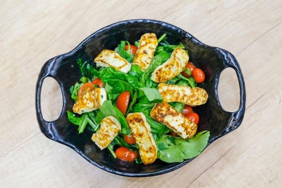 Salada de queijo com folhas de rúcula e tomates cereja.