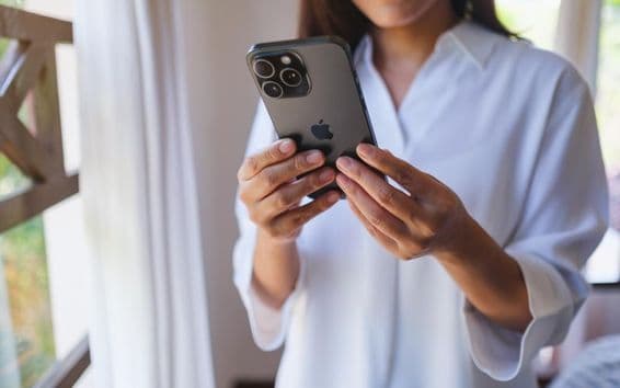 Uma mulher usando um iPhone 15 Pro Max em casa.