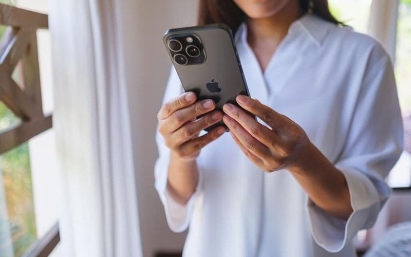 Uma mulher usando um iPhone 15 Pro Max em casa.