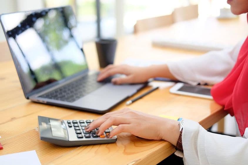 Trabalhadora em Dubai calculando dados financeiros com uma calculadora.
