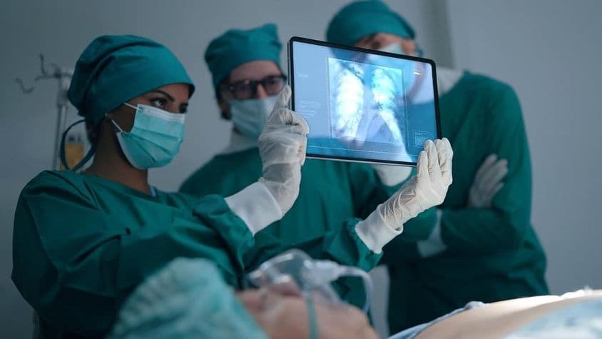 Equipe médica profissional discutindo e revisando um raio-X de um paciente com pneumonia.