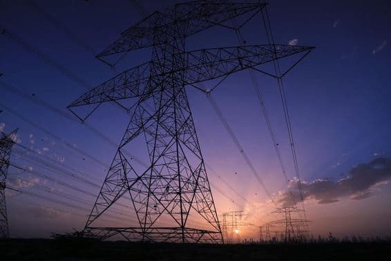 Torres de alta tensão sob o pôr do sol com vista para o cenário urbano de Dubai.