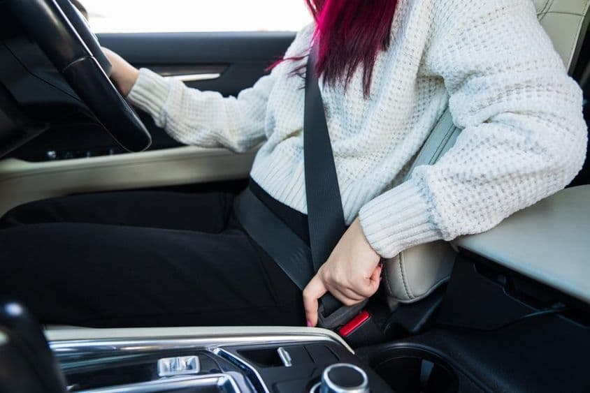 Motorista feminina colocando o cinto de segurança.