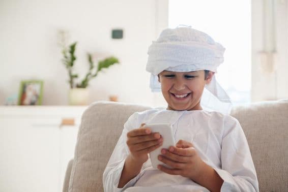 Menino árabe usando um smartphone em casa.