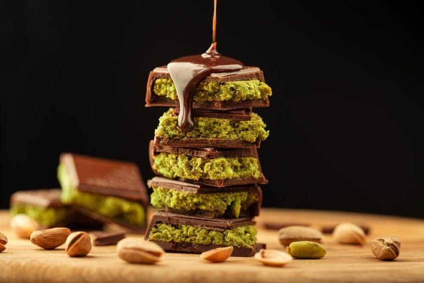 Chocolate de Dubai com pistaches e chocolate derramado sobre uma mesa.