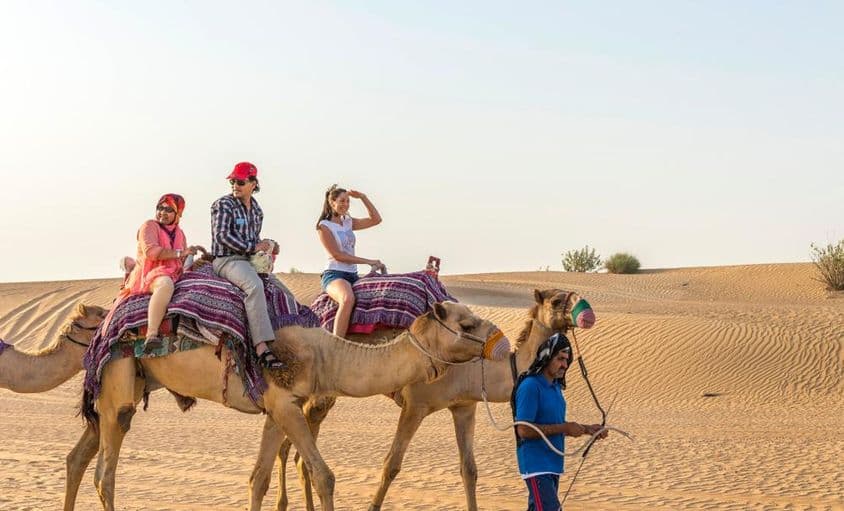 Turistas em um passeio de camelo no deserto de Dubai.