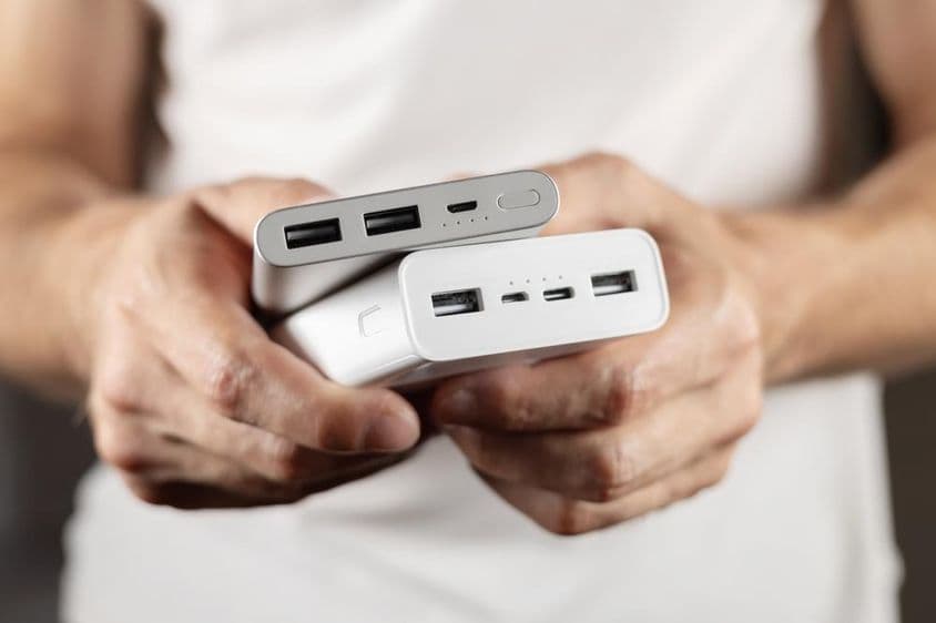 Duas baterias externas seguradas na mão.