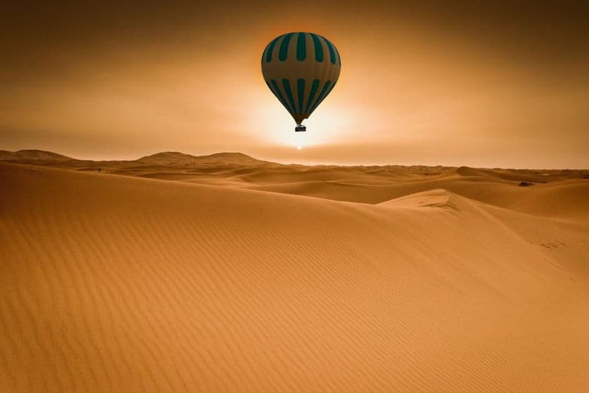 Paisagem do deserto e balão de ar quente ao nascer do sol.
