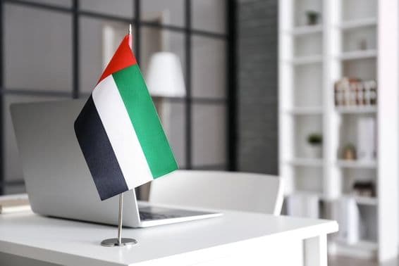 Bandeira dos Emirados Árabes Unidos sobre uma mesa em um escritório moderno.