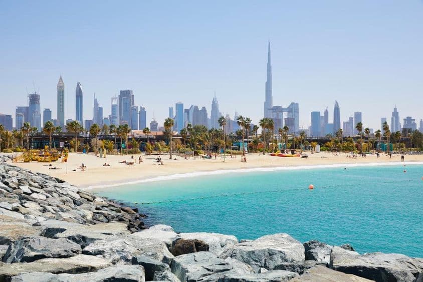 Praia La Mer com o horizonte de Dubai ao fundo, Emirados Árabes Unidos.