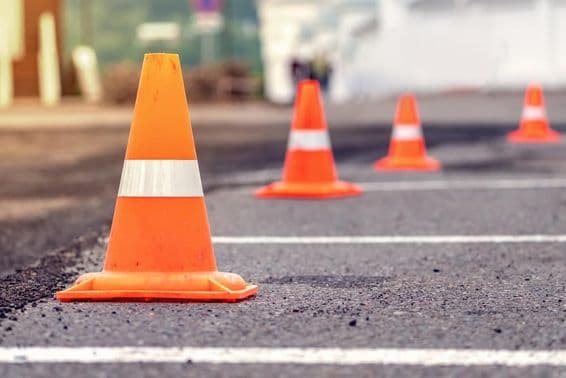 Linhas de cones de trânsito laranja brilhantes em uma estrada de asfalto.