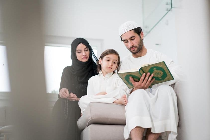 Pais jovens e um garotinho lendo um livro.