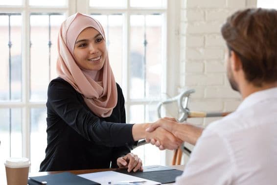 Gerente de RH árabe com hijab apertando a mão de um candidato a emprego do sexo masculino.