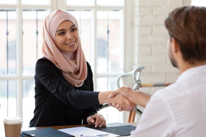 Gerente de RH árabe com hijab apertando a mão de um candidato a emprego do sexo masculino.