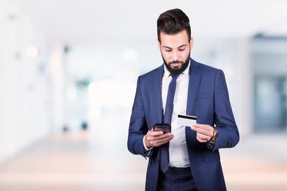 Empresário árabe segurando um smartphone e cartão de crédito.