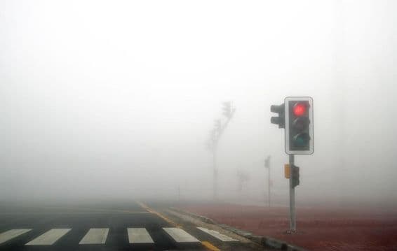 Névoa em uma estrada de Dubai, sinal vermelho piscando.