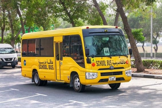 Ônibus escolar Toyota Coaster em rua da cidade de Dubai.