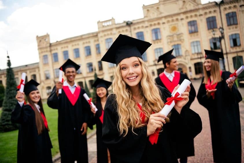 Jovens graduados alegres comemorando conquistas acadêmicas ao ar livre.