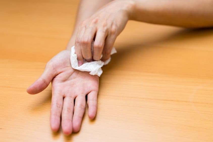 Mulher sofrendo com mãos suadas.