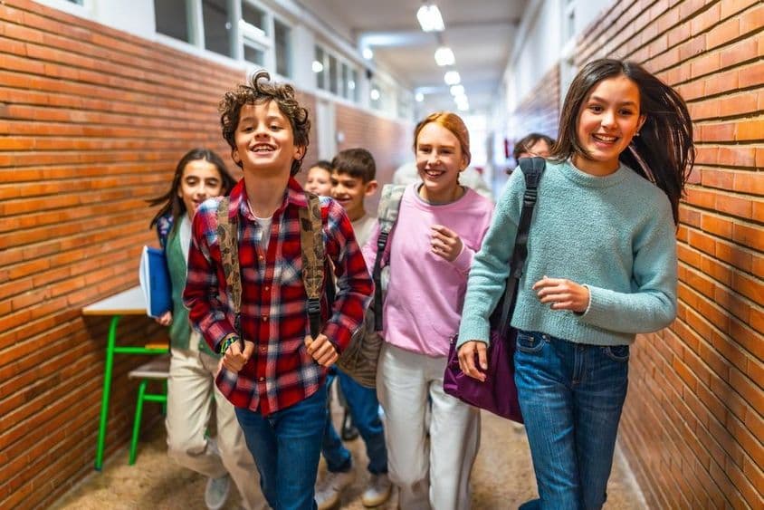 Alunos alegres correndo pelo corredor da escola.
