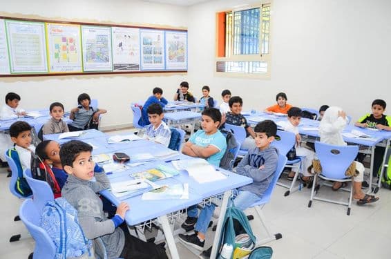 Uma sala de aula com um grupo de estudantes árabes aprendendo.