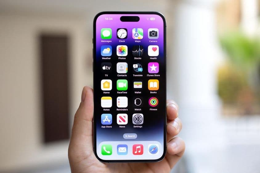Homem segurando um iPhone 15 Pro Max com iOS 17 na tela.