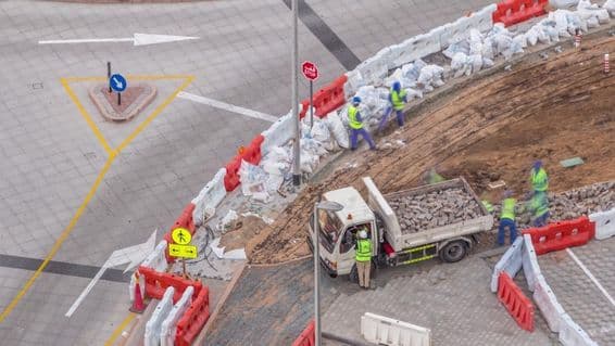 Processo de reparação de calçadas com muitos trabalhadores e equipamentos quebrando calçada e concreto.
