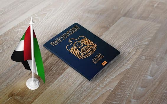 Passaporte dos Emirados Árabes Unidos sobre uma superfície de madeira, com uma bandeira nacional.