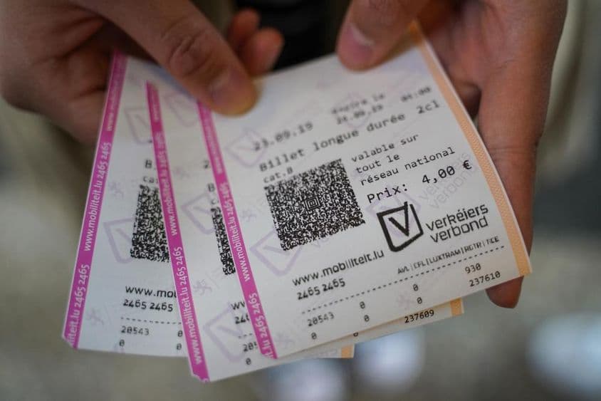 Um jovem segurando ingressos na mão.