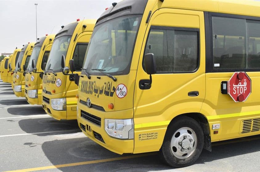 Vários ônibus escolares amarelos alinhados em um estacionamento em Dubai.