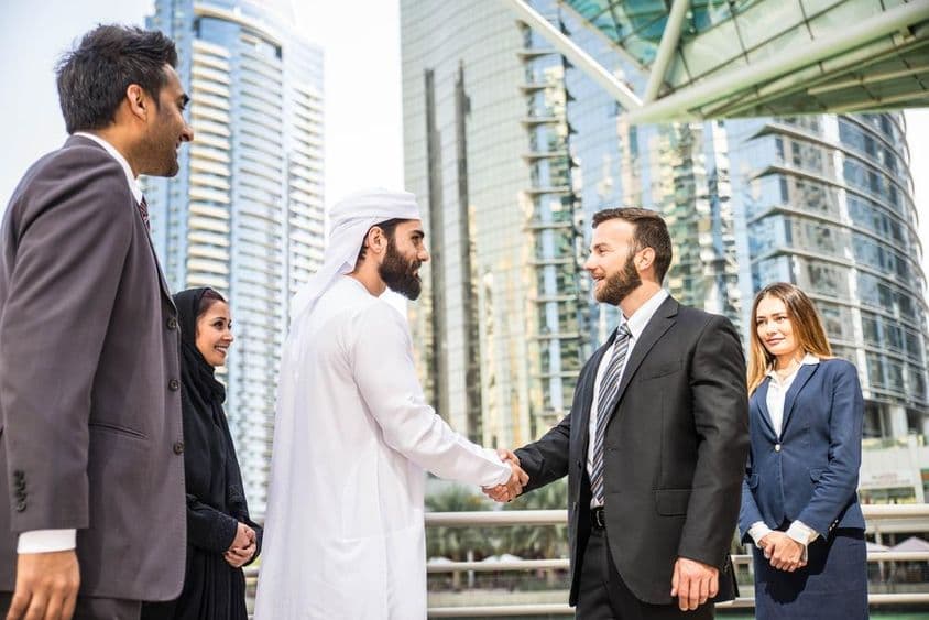 Grupo multinacional de empresários reunidos ao ar livre em Dubai.