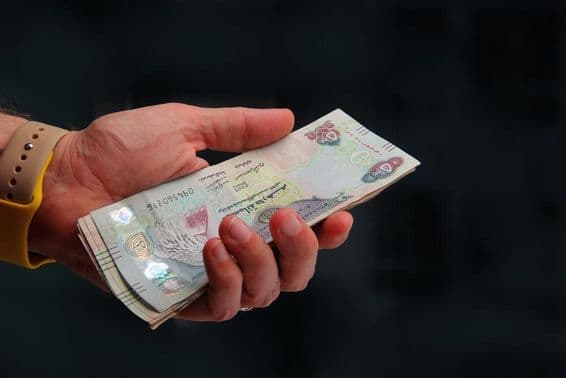 Emirados Árabes Unidos, dirham de Dubai na mão de um homem.
