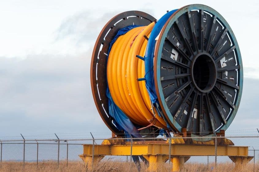 Enorme cabo industrial de fibra óptica subaquático em um carretel de metal no convés de um navio.