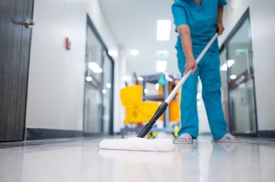 Faxineiro passando pano no chão do corredor.