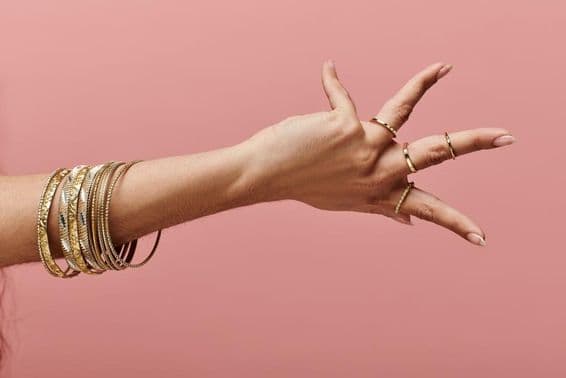 Mulher indiana elegantemente posando com braceletes de ouro no pulso.
