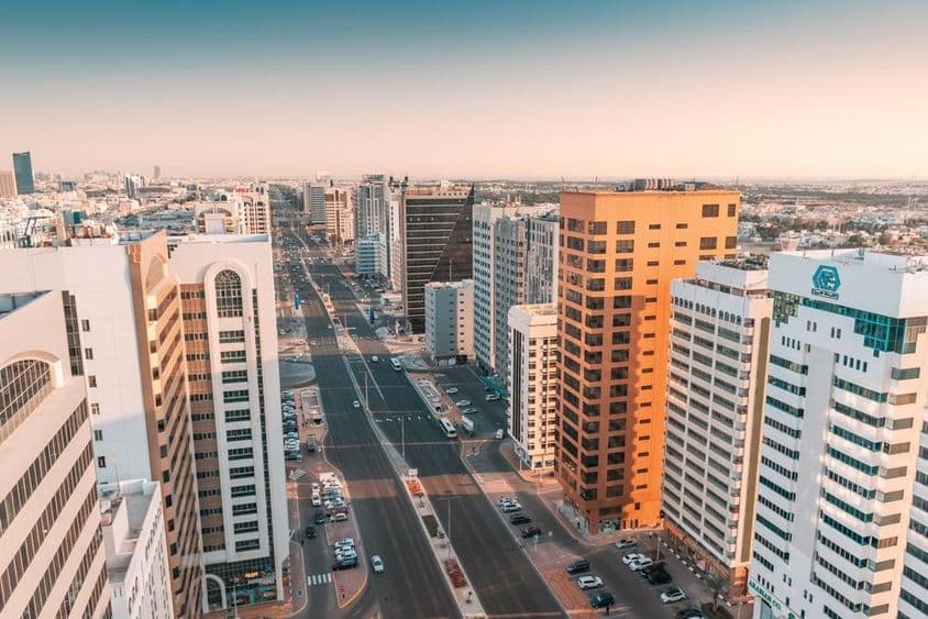 Abu Dhabi, visão aérea de uma ampla avenida com tráfego passando entre arranha-céus.