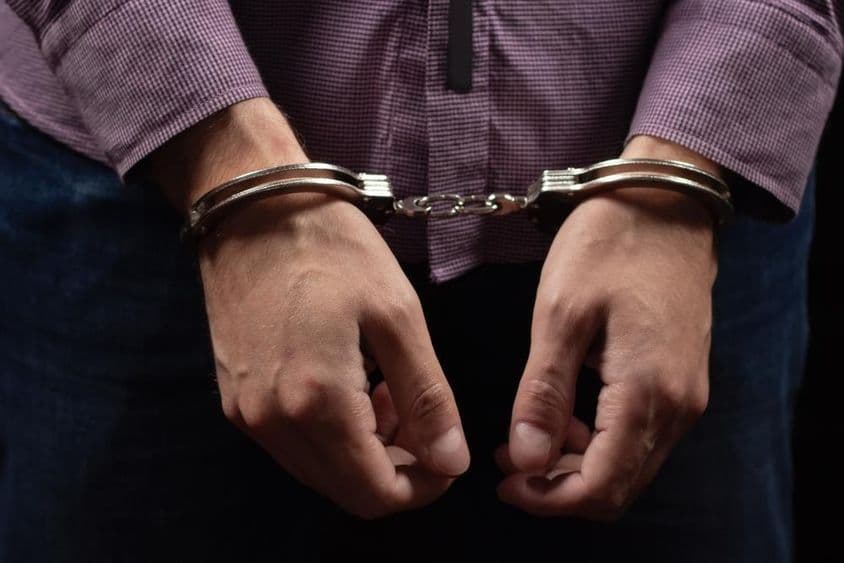 Ladrão preso em algemas por roubo e fraude.
