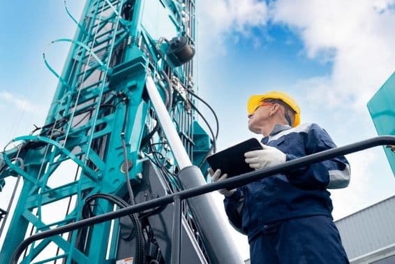 Operador industrial usando um tablet digital para controlar uma plataforma de perfuração.