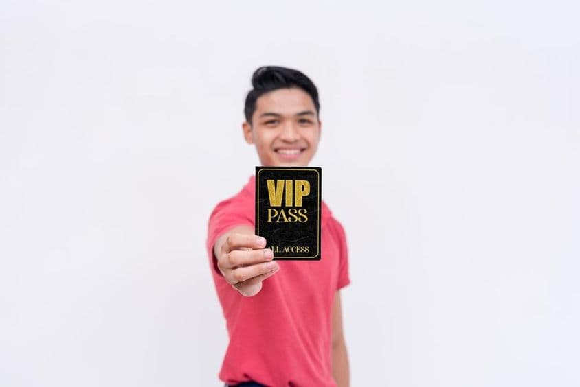 Um homem feliz segurando um ingresso ou crachá VIP.