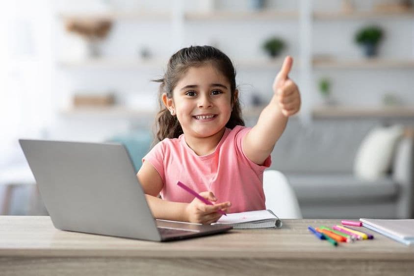 Menina árabe aprendendo em casa com um laptop, mostrando positivo.