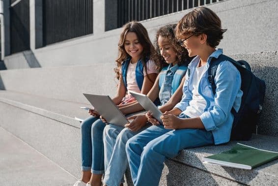 Crianças escolar felizes, meninos adolescentes usando um tablet.