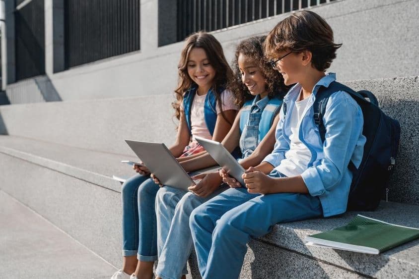 Crianças escolar felizes, meninos adolescentes usando um tablet.