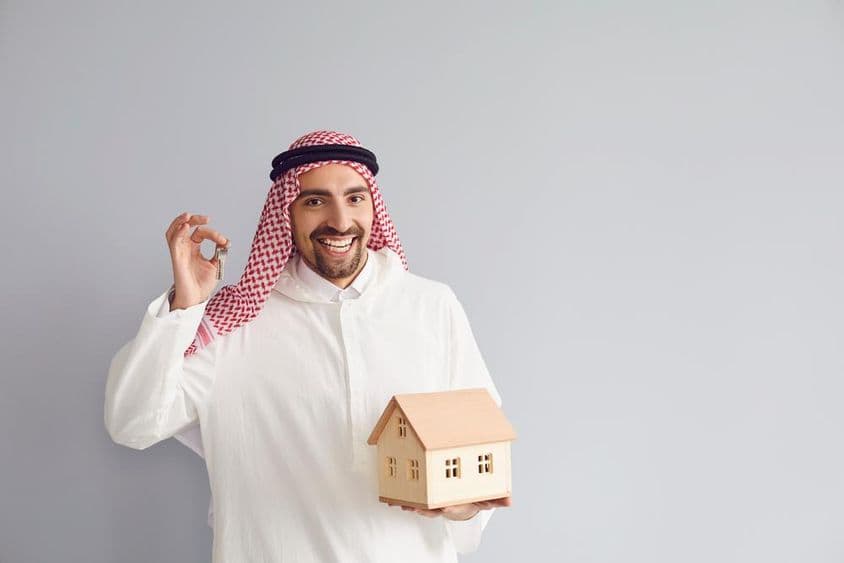 Agente imobiliário árabe segurando um modelo de casa.