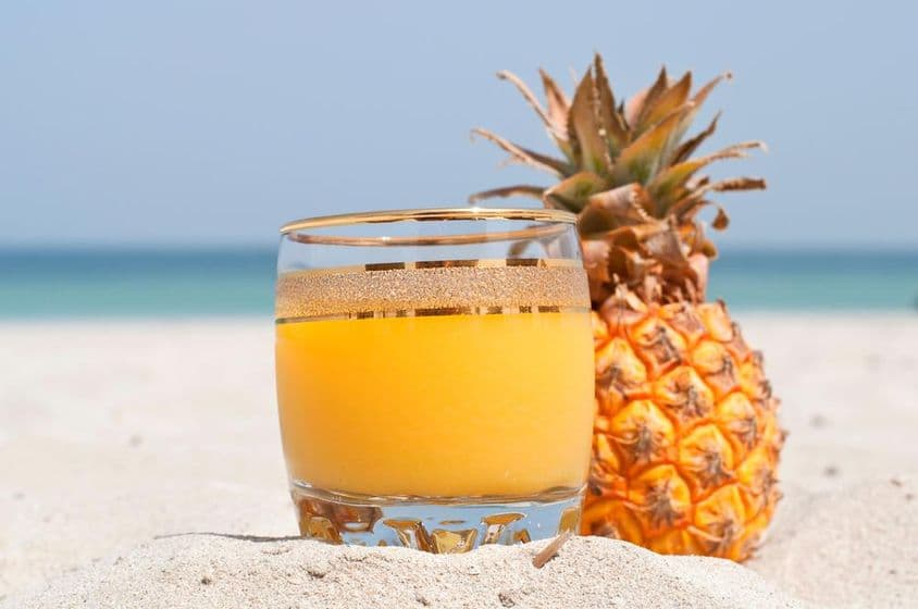 Um copo de suco de abacaxi na praia.