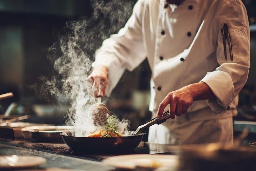 Um chef cozinhando na cozinha.