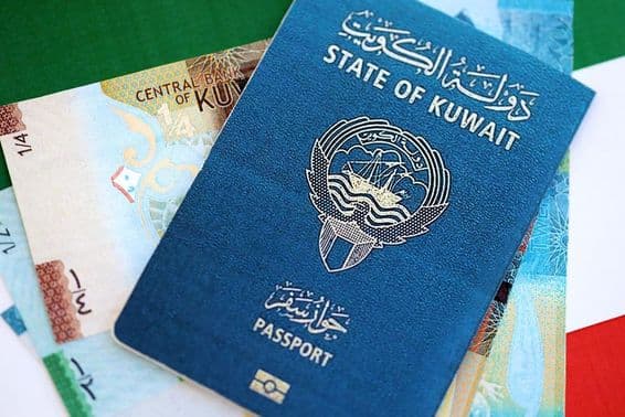 Dinar kuwaitiano e passaporte em uma mesa.