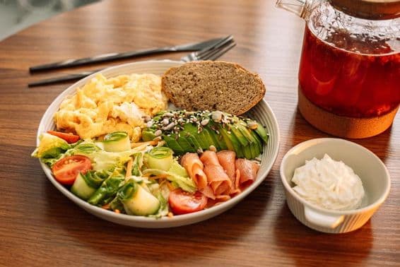 Café da manhã saudável com ovos, abacate, verduras, salada e chá de framboesa.